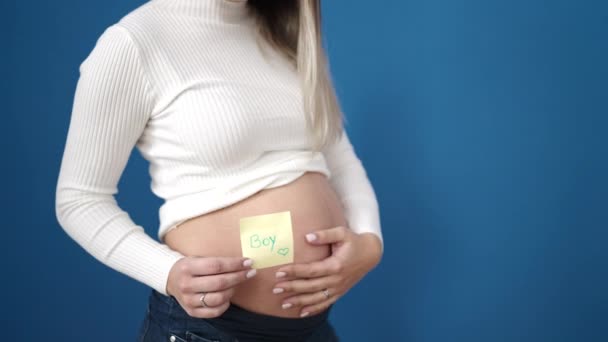 Jong Zwanger Vrouw Zetten Jongen Herinnering Papier Buik Geïsoleerde Blauw — Stockvideo