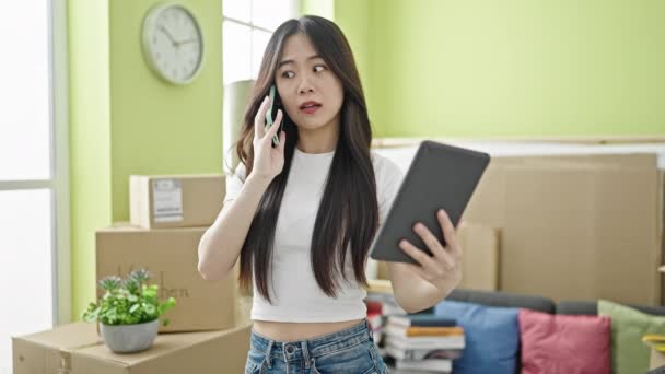 Ung Kinesisk Kvinna Talar Smartphone Med Pekplatta Nytt Hem — Stockvideo