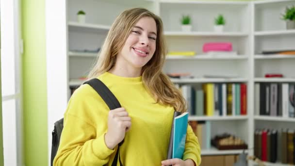Młoda Blondynka Student Uśmiecha Się Pewnie Trzymając Książki Uniwersytecie Bibliotece — Wideo stockowe