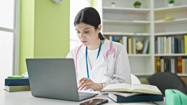 Jovem Bela Mulher Hispânica Médico Estressado Livro Leitura Usando Laptop — Vídeo de Stock
