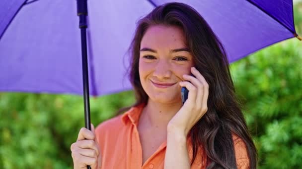 Jovem Bela Mulher Hispânica Segurando Guarda Chuva Falando Smartphone Parque — Vídeo de Stock