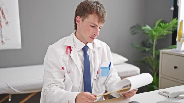 Młody Biały Mężczyzna Lekarz Czytanie Dokument Schowku Klinice — Wideo stockowe