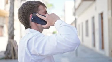Beyaz bir adam sokakta akıllı telefondan konuşuyor.