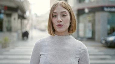 Genç sarışın kadın gülümsüyor. Kendinden emin konuşuyor.