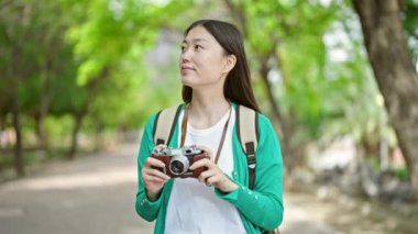 Parkta kamera kullanarak sırt çantası takan Çinli genç bir turist.