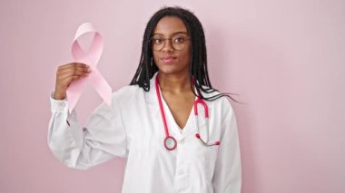 Göğüs kanseri olan Afrikalı Amerikalı kadın doktor pembe bir kurdele takıyor.