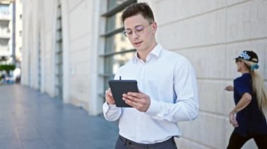 Latin kökenli genç iş adamı güler yüzlü. Sokakta dokunmatik bloknotlarda kendine güveni olan.