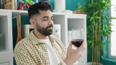 Genç İspanyol adam yemek odasındaki masada oturmuş şarap içiyor.