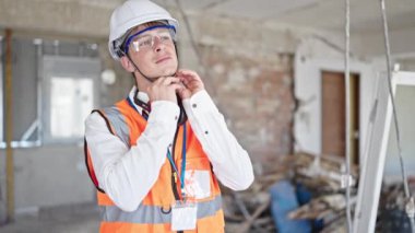 Kafkasyalı genç mimar gülümsüyor inşaat alanında kaskını çıkarıyor.