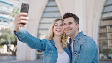 Kadın ve erkek yan yana durur. Sokakta akıllı telefonlardan selfie çekerler.