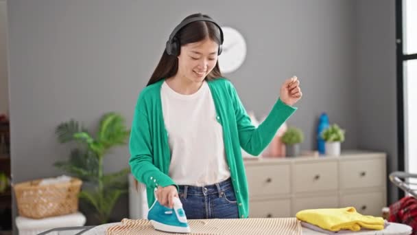 Junge Chinesin Hört Musik Beim Bügeln Von Kleidern Und Tanzt — Stockvideo