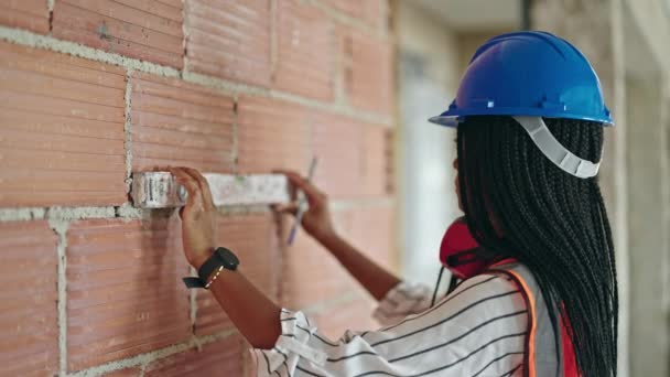 非洲裔美国女建筑工人站在建筑工地上 用宽松的表情测量墙壁 — 图库视频影像