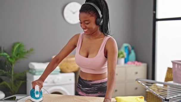 Afroamerikanerin Hört Musik Beim Bügeln Von Kleidung Der Waschküche — Stockvideo