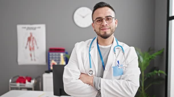 西班牙男人医生面带微笑 自信地站在诊所里 双手交叉地摆出姿势 — 图库视频影像