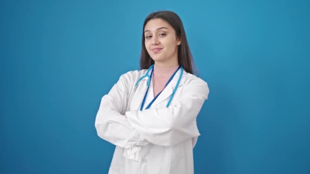 年轻美丽的惊慌失措的女医生微笑着 自信地站在那里 双手交叉地在孤立的蓝色背景上做着手势 — 图库视频影像