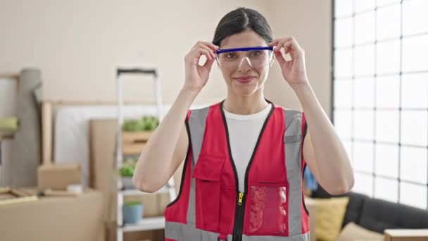 年轻美丽的惊慌失措的女建筑工人微笑着 自信地摘下新家的眼镜 — 图库视频影像