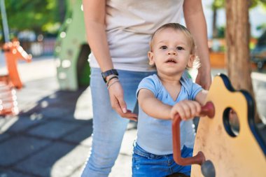 Anne ve oğlu parkta salıncakta sallanıyor.