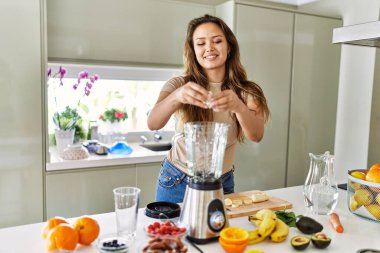 Genç, güzel İspanyol kadın mutfakta sebze suyu ve blender hazırlıyor.