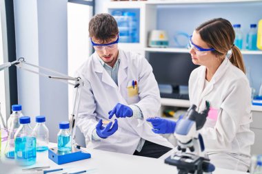 Genç adam ve kadın bilim adamları laboratuarda çalışıyorlar.