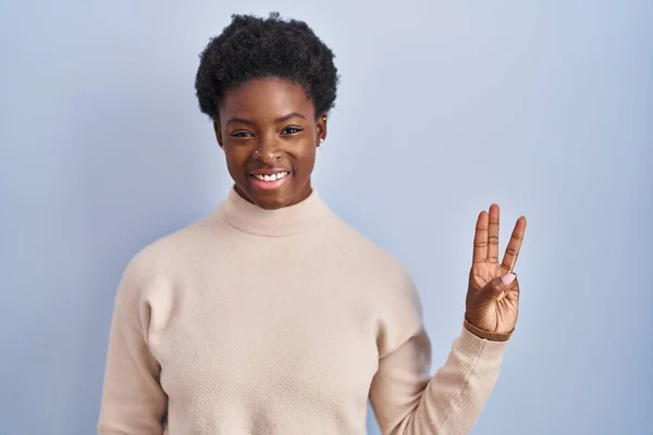 Африканская Американка Стоит Синем Фоне Показывает Пальцем Номер Три Улыбаясь — стоковое фото