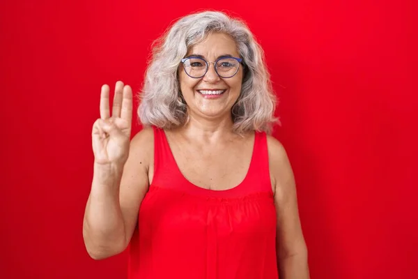 Kırmızı Arka Planda Duran Gri Saçlı Orta Yaşlı Kadın Numaralı — Stok fotoğraf