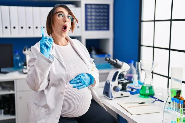 Těhotná Žena Pracující Laboratoři Vědec Užaslý Překvapený Vzhlíží Ukazuje Prsty — Stock fotografie