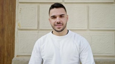 Genç İspanyol adam gülümsüyor. Kendine güveniyor. Sokakta elleriyle jest yapıyor.