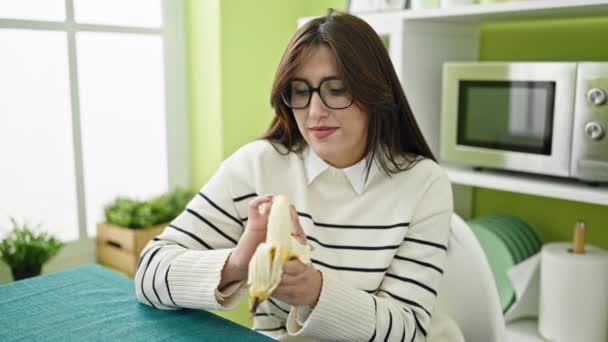 Junge Schöne Hispanische Frau Lächelt Selbstbewusst Und Isst Banane Esszimmer — Stockvideo