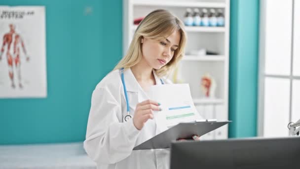 Young Blonde Woman Doctor Reading Document Clipboard Clinic — Stock Video