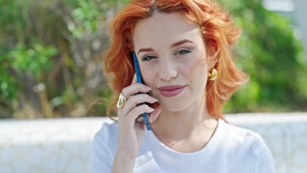年轻的红头发女人在公园里用智能手机笑着 — 图库视频影像