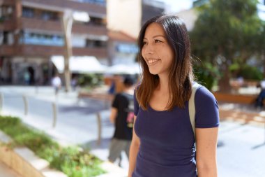 Young asian woman smiling confident looking to the side at street