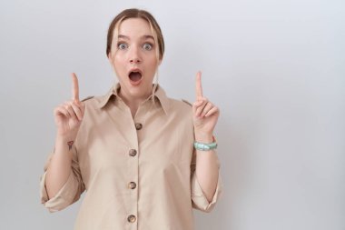 Gündelik tişört giyen genç beyaz kadın şaşkın şaşkın gülüyor, parmaklarıyla işaret ediyor ve kollarını kaldırıyordu.. 