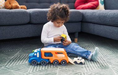 Sevimli İspanyol kız evde yerde oturmuş oyuncaklarla oynuyor.