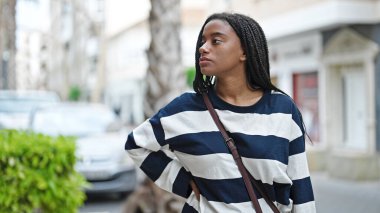 Sokakta ciddi bir ifadeyle yan tarafa bakan Afrikalı Amerikalı kadın.