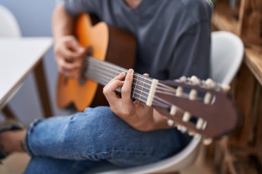 Young caucasian man playing classical guitar at home