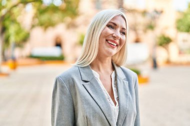 Parkta kendinden emin gülümseyen genç sarışın kadın.