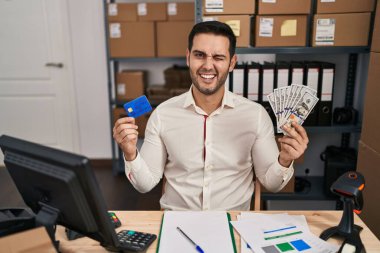 Sakallı, küçük işletme şirketinde çalışan, elinde banknotlar ve kredi kartı tutan seksi bir ifadeyle kameraya bakan, neşeli ve mutlu yüzlü genç bir İspanyol.. 