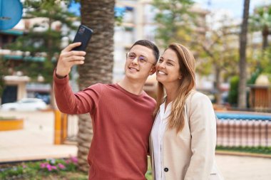 Erkek ve kadın, anne ve oğul gülümsüyor. Parktaki akıllı telefondan özçekim yapıyorlar.