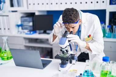 Laboratuvarda mikroskop kullanan Afrikalı Amerikalı bilim adamı.