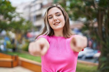Young woman smiling confident pointing with fingers at park