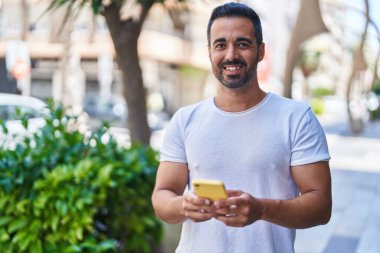 Sokakta akıllı telefon kullanan, kendine güvenen genç bir İspanyol.