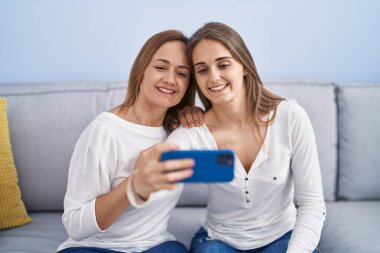 Two women mother and daughter make selfie by smartphone at home