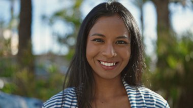 Afro-Amerikalı kadın parkta kendinden emin bir şekilde gülümsüyor.