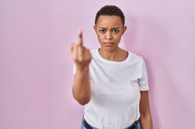 Beautiful african american woman standing over pink background showing middle finger, impolite and rude fuck off expression 