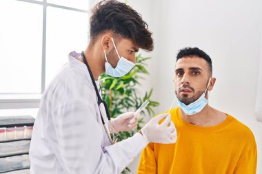 Klinikte antijen testi yapan iki adam ve hasta.