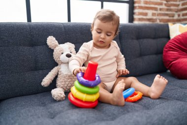 Sevimli İspanyol bebek evdeki kanepede oturmuş basketbol oynuyor.
