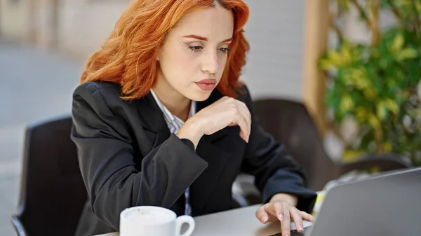 コーヒーショップのテラスでリラックスした表情でラップトップを使用して若い赤毛の女性のビジネスワーカー — ストック写真