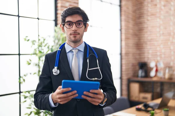 Young Hispanic Man Wearing Doctor Stethoscope Office Relaxed Serious Expression — Stock Photo, Image