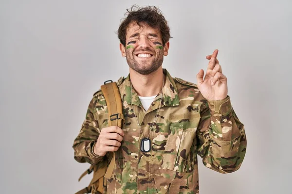 カモフラージュ軍の制服を着たヒスパニック系の若者が希望と目を閉じて笑顔を越えジェスチャー指 幸運と迷信の概念は — ストック写真