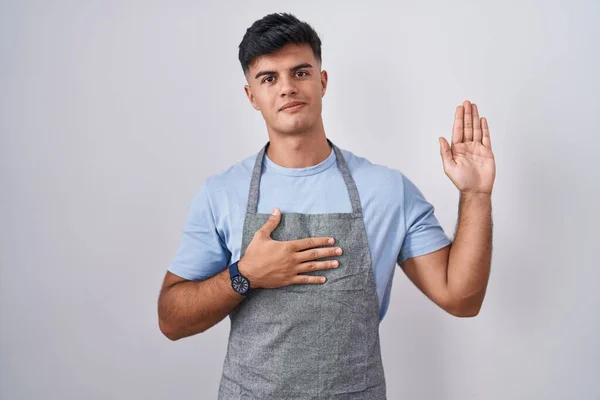 Hispanic Young Man Wearing Apron White Background Swearing Hand Chest — Stock Photo, Image
